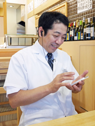 スマートフォンを操作する三浦友久専務